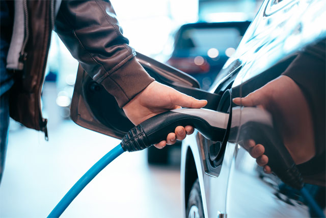 human hand is holding electric car charging connect electric car