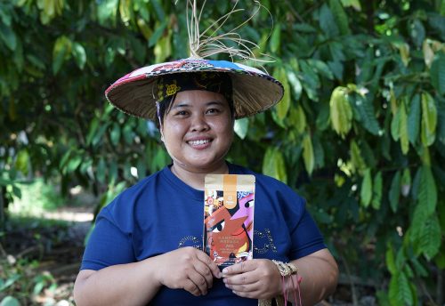 Indonesian cocoa farmer in Kampung Merasa, Berau Regency, East Kalimantan, posing with a premium chocolate product made with local cocoa beans.