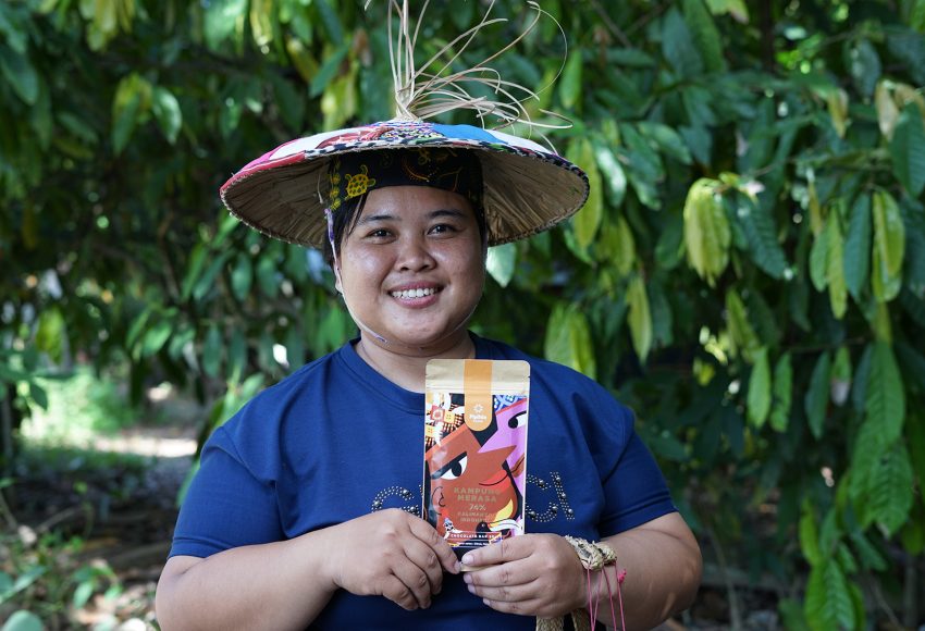 Indonesian cocoa farmer in Kampung Merasa, Berau Regency, East Kalimantan, posing with a premium chocolate product made with local cocoa beans.